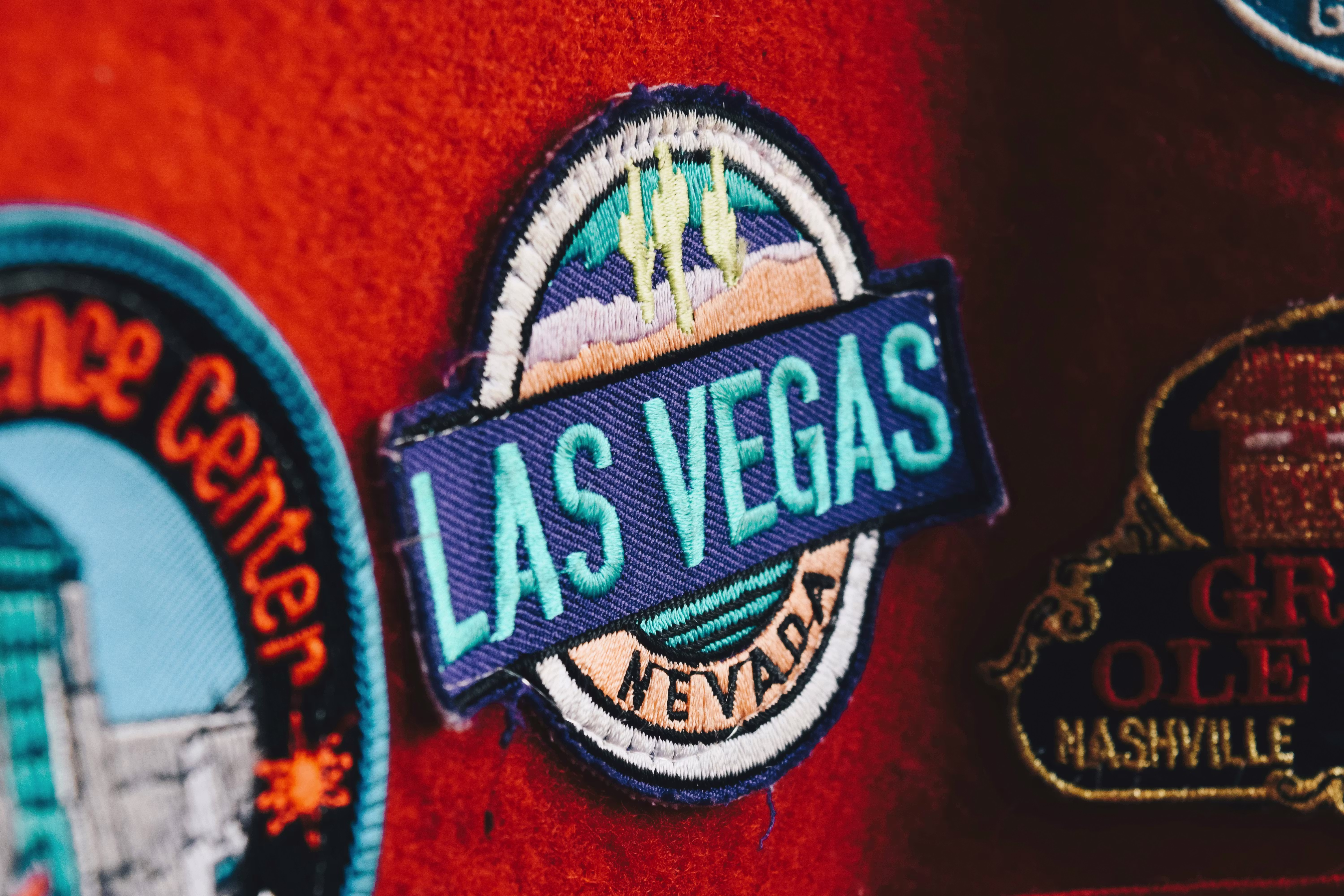 A close-up of an embroidered "Las Vegas" patch on a red fabric background