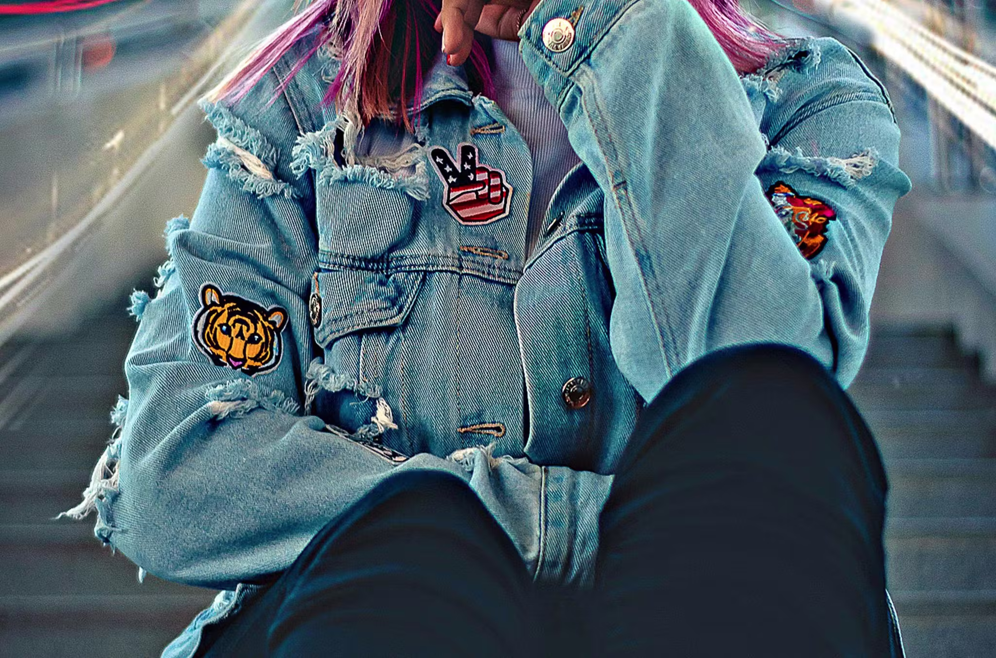 a close up of a girl wearing a jean jacket with patches on it