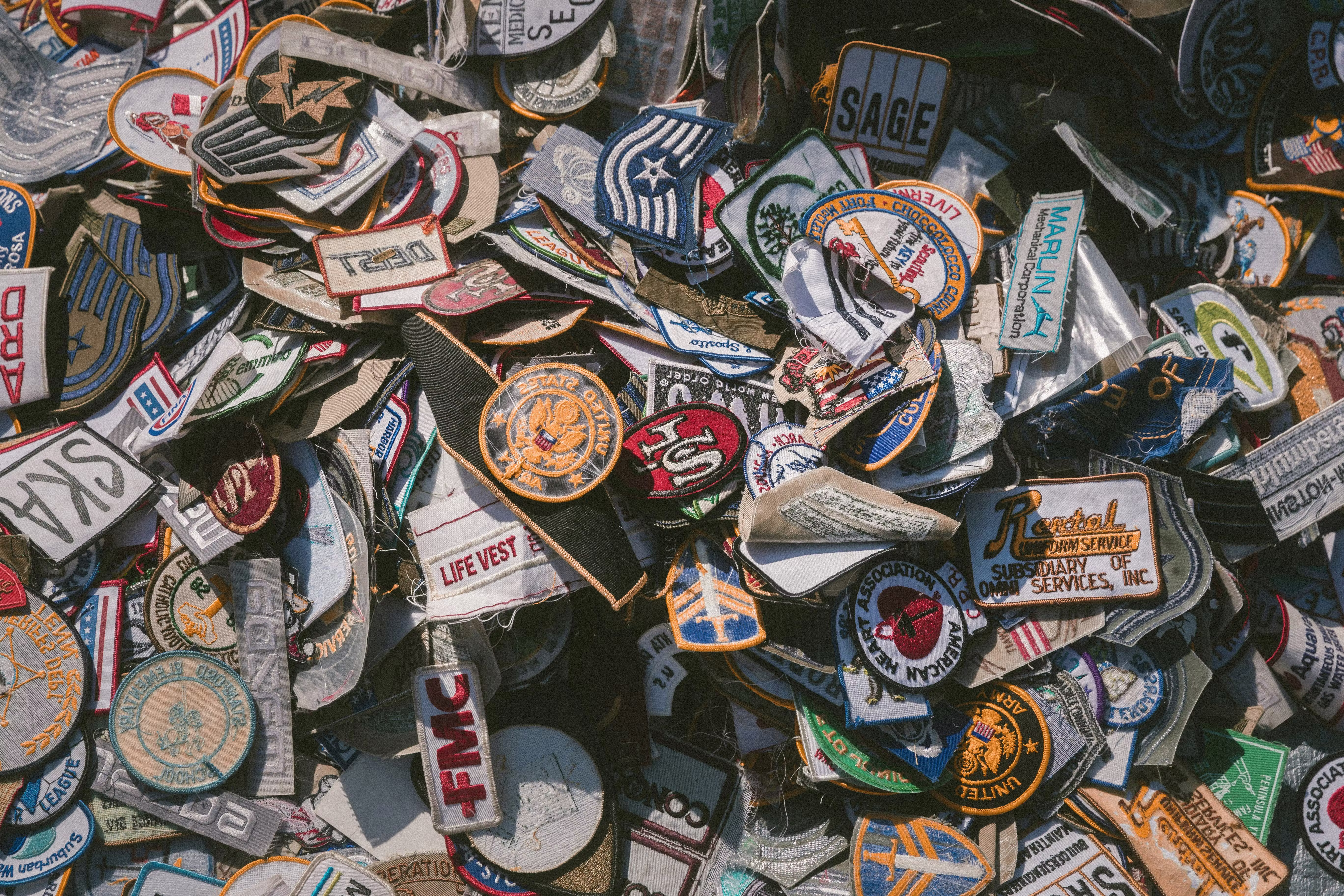 Custom embroidered patches in various shapes, colors, and designs piled together