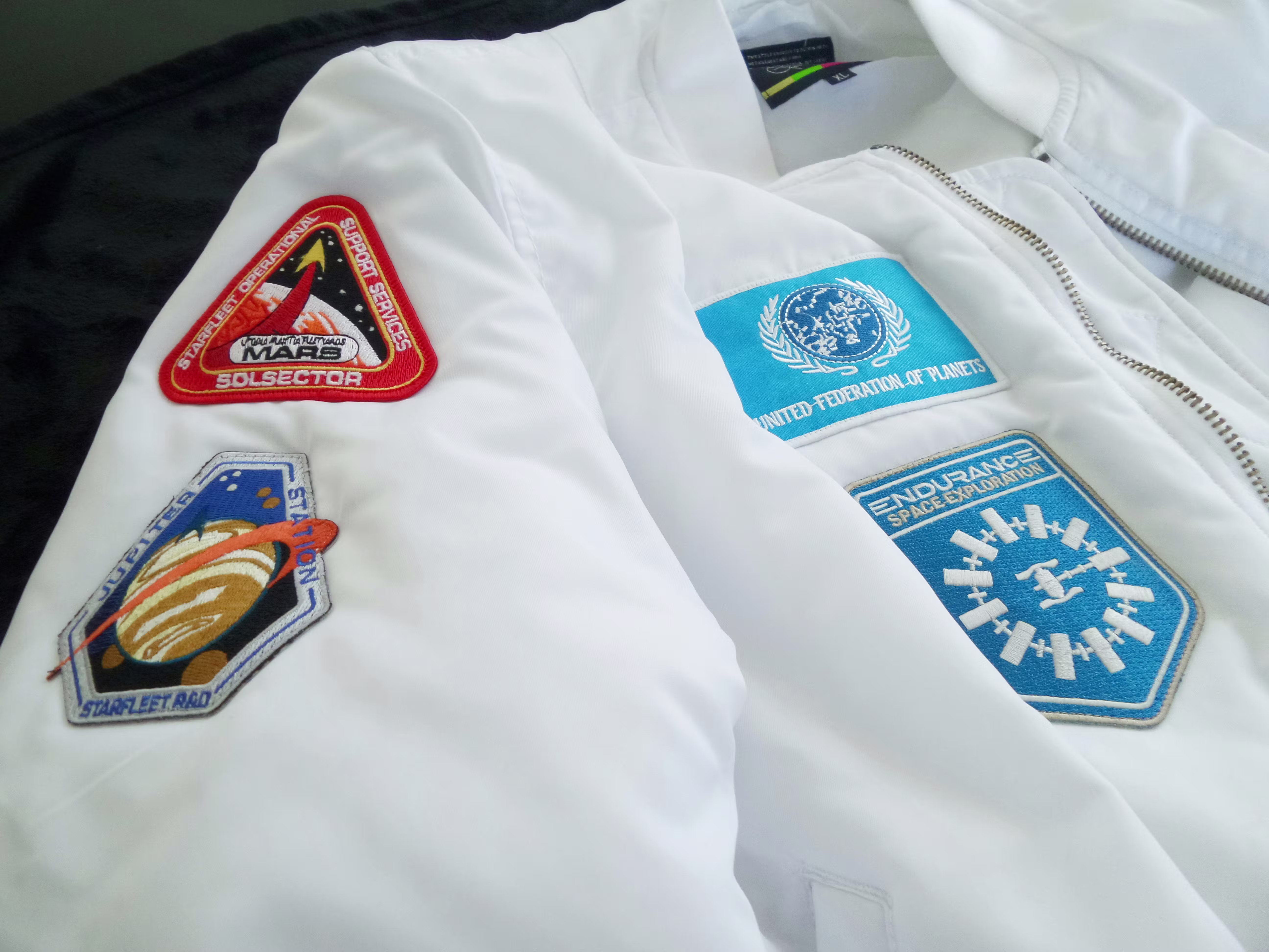 a white puffer jacket with patches attaches to the front and arm